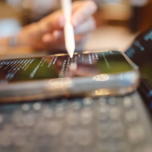 Hand, die mit einem weißen Eingabestift auf dem Display eines Smartphones tippt.